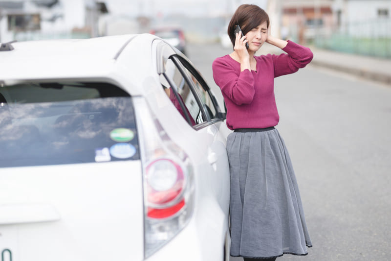 車に寄りかかり困り顔の女性